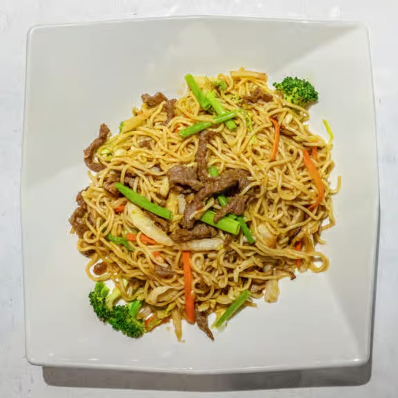 King Ocean Crab's beef lo mein with noodles, broccoli, carrots, and green onions on a white plate.